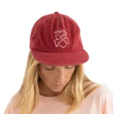 Gorra de visera color rojo con bordado frontal que incluye el logo floral y la palabra 'Rhythm'.
