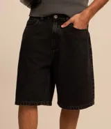 Bermuda baggy de jean color negro con pespuntes contrastantes, cierre de botón y cremallera, y bolsillos.