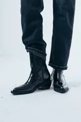 Bota de caña media confeccionada en cuero negro con acabado brillante, diseño de silueta limpia, puntera cuadrada y taco cuadrado de altura media.