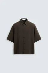 Camisa de corte relajado confeccionada en tejido con mezcla de modal, con cuello solapa, manga corta y cierre frontal de botones.