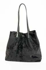 Bolso tipo tote de gran tamaño en color bordó, confeccionado en material con textura similar a la gamuza. Cuenta con doble asa larga para llevar al hombro y una pequeña placa metálica decorativa en el frente.