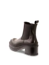 Botas Chelsea de cuero negro con elástico lateral, caña baja, suela track y taco bloque.