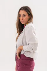 Camisa beige a rayas finas de manga larga, con cuello camisero y cierre frontal oculto.