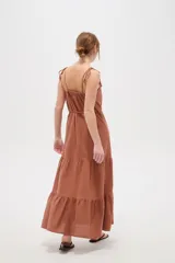 Vestido largo de algodón color blanco, con tirantes finos ajustables con lazos en los hombros, escote recto decorado con apliques florales tridimensionales, cordón ajustable en la cintura y falda larga con volados horizontales.