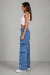 Jean de tiro medio con corte wide leg, confeccionado en denim azul. Presenta un diseño distintivo con apliques en forma de estrella con bordes deshilachados y bolsillos laterales tipo cargo.