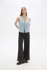 Chaleco de jean celeste con escote en V y cierre frontal con lazos.