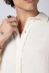 Camisa de manga larga color crema, confeccionada en lino, con cuello clásico y corte holgado.