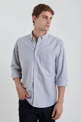 Camisa gris de algodón Oxford, manga larga con puños abotonados y cuello button-down. Tiene un bolsillo de parche en el pecho.