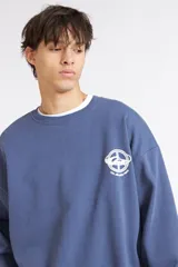 Buzo Quiksilver azul con cuello redondo, diseño oversize y pequeño estampado gráfico blanco en el pecho.