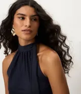 Blusa sin mangas color azul marino, con cuello alto y detalle de lazo integrado en el escote.