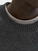 Sweater de punto con diseño de bloques de color en tonos grises y negros, manga larga, cuello redondo y ajuste relajado. Presenta puños y cuello acanalados con una textura suave y elástica.