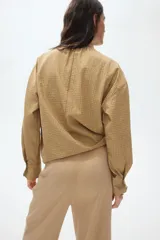 Pantalón de punto color beige con cintura elástica fruncida, piernas amplias, pliegues delanteros y ribetes laterales en color blanco.