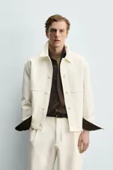 Sobrecamisa marrón de corte boxy fit en tejido compacto, con cuello solapa, manga larga con puños abotonados, bolsillos frontales de parche y cierre central de botones.