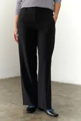 Pantalón marrón de corte recto y pierna ancha, con cintura alta, bolsillos laterales y cierre.