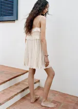 Vestido corto color crudo, con tirantes finos, detalles de encaje y volados en el pecho.