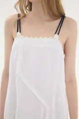Vestido midi de lino color salmón, de corte amplio y silueta holgada. Presenta diseño con cortes irregulares y detalles de pasamanería en el escote y costuras. Cuenta con breteles dobles tipo cuerda y ruedo asimétrico.