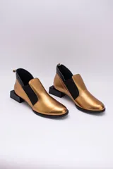 Zapato de cuero color dorado con elásticos laterales negros, taco cuadrado negro y tirador trasero.
