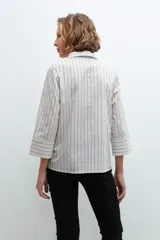 Blusa color beige con rayas verticales azules, cuello camisero, mangas 3/4 y cierre con botón.