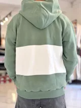 Hoodie de felpa con capucha y medio cierre frontal, diseño en bloques de color celeste y blanco, con bordados decorativos en el pecho.