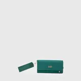 Billetera rectangular de diseño alargado, color gris, con solapa frontal y logo metálico de la marca. Incluye una correa de muñeca de tela con el nombre de la marca grabado.