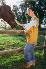 Chaleco mostaza de lana merino con tejido trenzado, corte oversized y largo asimétrico.