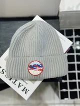 Gorro de lana gris con detalle de parche circular con diseño de montañas y cielo.