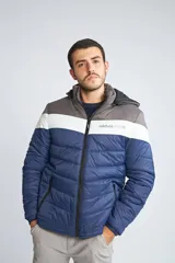 Campera inflada de abrigo para hombre, con capucha desmontable, cierre frontal completo, bolsillos con cierre y logo estampado. Diseño color block en azul, blanco y gris.