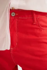 Pantalón de corte recto y tiro medio con costuras a la vista, bolsillos delanteros y traseros, y un detalle de pin de la marca en el ruedo.