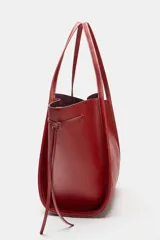 Bolso tipo shopper color rojo de hombro, con detalle de lazos en los laterales y doble asa.