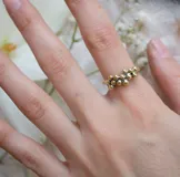 Anillo dorado con diseño de racimo de pequeñas esferas.