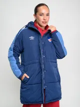 Parka larga de abrigo Umbro del Club Nacional de Football, con capucha, cierre frontal y botones a presión. Diseño en azul marino con detalles en azul claro en las mangas y escudo del club en el pecho.