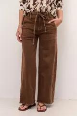 Pantalón de jean marrón con corte recto y amplio, tiro alto con presillas y lazo ajustable del mismo género. Presenta costuras decorativas pespunteadas a contratono y ruedo deshilachado con terminación en flecos.