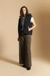 Chaleco acolchado de nylon color negro, con diseño capitoneado, capucha integrada y cierre frontal con tirador metálico.