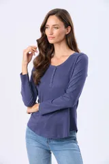 Remera de manga larga en color azul, confeccionada en tejido de algodón con textura jaspeada. Presenta un cuello redondo con tapeta frontal y botones a tono, y un ruedo ligeramente curvo.