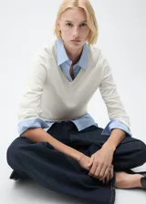 Jersey de punto fino en color crudo, con cuello en pico y diseño de corte recto con manga larga.