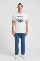 Remera blanca de manga corta y cuello redondo, con estampado gráfico frontal en tonos oscuros con la leyenda "Otherside Expedition Co." y el diseño de una ballena.