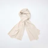 Bufanda de punto suave en color beige, con diseño liso y terminaciones desflecadas en los extremos.