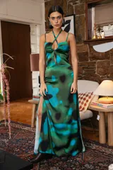 Vestido largo de satén con estampado abstracto en tonos verdes y azules, con escote halter cruzado, detalle de frunce en el pecho y tajo lateral profundo.