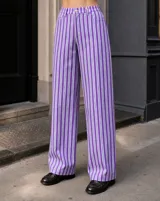 Pantalón de corte recto y tiro alto con estampado de rayas verticales en tonos morado, blanco y azul. Cuenta con presillas para cinturón y cierre frontal con botón y cremallera.
