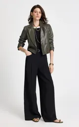 Pantalón sastrero de tiro alto en color negro, con corte ancho y fluido. Presenta pliegues delanteros, cintura estructurada con trabillas y bolsillos laterales. Incluye un cinturón de tela a juego con hebilla metálica ovalada.