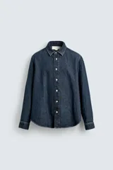 Camisa de corte relajado confeccionada en denim de algodón, con cuello solapa, manga larga con puños abotonados y cierre frontal de botones.