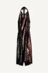 Vestido largo de lentejuelas con cuello halter, espalda descubierta y lazos para atar al cuello. Cuenta con un cinturón de lazo en contraste y diseño bicolor que combina tonos tostados y negros.