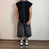 Musculosa negra de corte holgado con costuras blancas a la vista en cuello, sisas y ruedo.