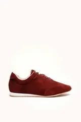 Zapatilla de gamuza color bordó con cordones bicolores, interior de cuero vacuno y suela de caucho blanca y beige.