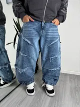 Pantalón jeans baggy de corte amplio y relajado, color azul con efecto deslavado y detalles de costuras horizontales deshilachadas.