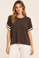 Remera marrón de punto, de corte holgado y manga corta con detalles de rayas blancas en los puños, con cuello redondo.
