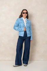 Chaqueta tipo biker de cuero ecológico en color celeste con efecto desgastado. Presenta cierre frontal asimétrico, bolsillos con cierre metálico, cuello con solapas y detalles de tachas decorativas.