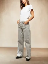 Jean de corte recto y tiro medio en color bordeaux, con detalle de tachas metálicas a lo largo de las costuras laterales y ruedo desflecado.