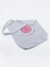 Bolso tipo tote de tela color blanco con asas largas. Estampado circular en color rosa con texto "EN LA LUCHA ESTAMOS JUNTOS".