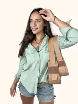 Bolso tipo baguette de cuero genuino color marrón claro, con dos compartimentos frontales con solapa y un parche de gamuza con el logo de un búho grabado. Posee una correa ancha de cuero ajustable.